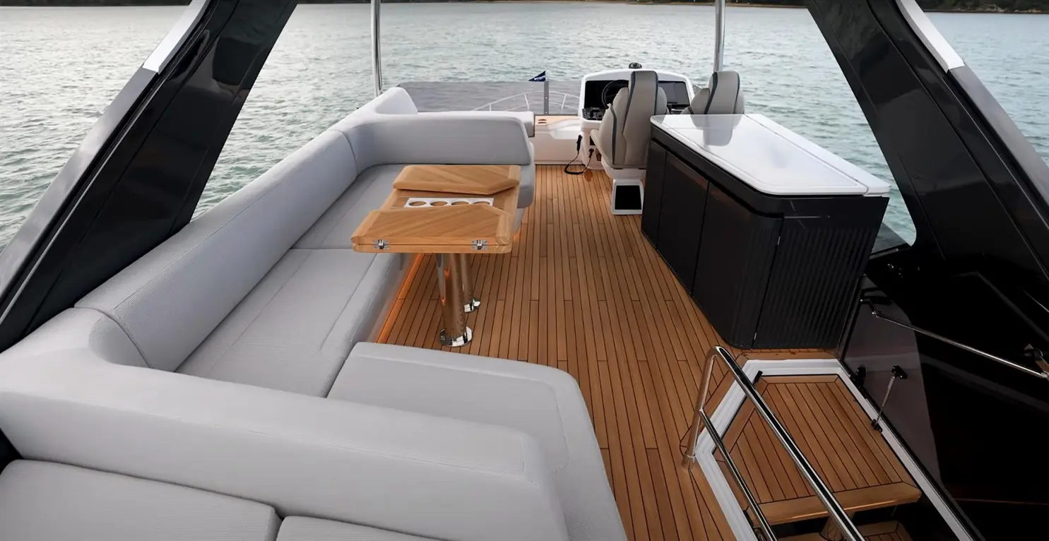 Stylish yacht interior showcasing plush seating, wooden tables, and a modern helm by the serene water.